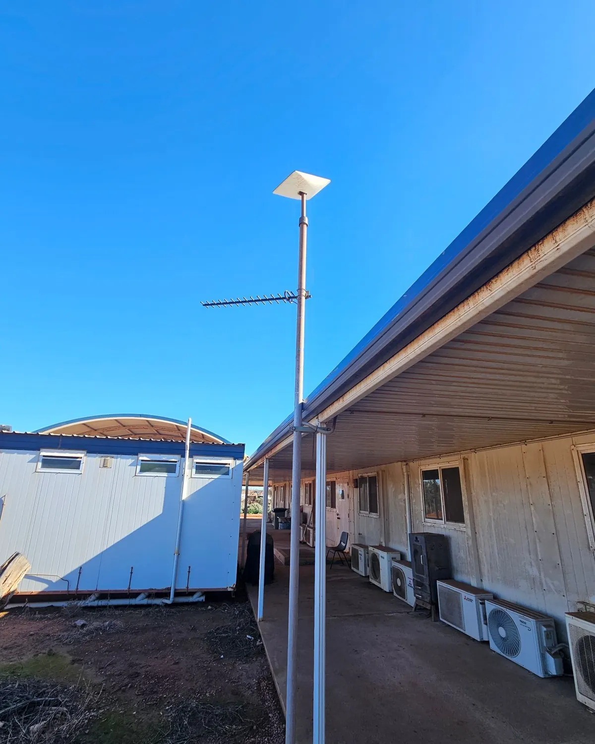 A Starlink dish and a Yagi antenna on a pole beside the accommodation buildings at a remote outback camp